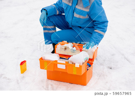 Young paramedic in workwear and gloves checking medicine and first aid items Young paramedic in workwear and gloves checking medicine and first aid items 59657965