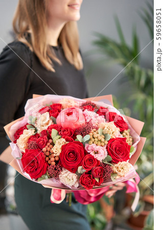 Red tones Beautiful bouquet of mixed flowers in womans hands. the work of the florist at a flower Red tones Beautiful bouquet of mixed flowers in womans hands. the work of the florist at a flower 59658051