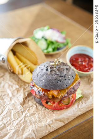 Cheeseburger with lettuce, tomato, fries, and melted cheese. The table in the restaurant. Unhealthy Cheeseburger with lettuce, tomato, fries, and melted cheese. The table in the restaurant. Unhealthy 59658340