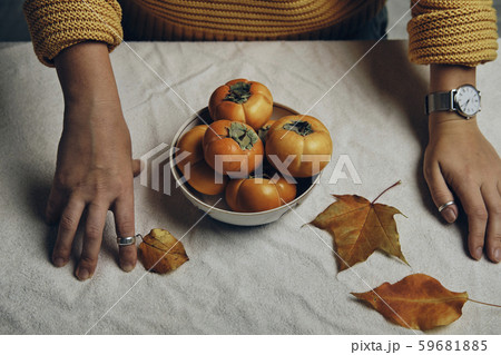 Hand holding dish with fresh orange persimmons 59681885