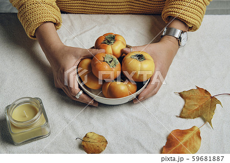 Hand holding dish with fresh orange persimmons 59681887