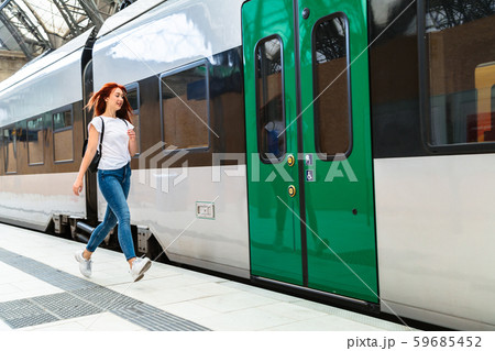 Woman at train station hurries to electric train Woman at train station hurries to electric train 59685452