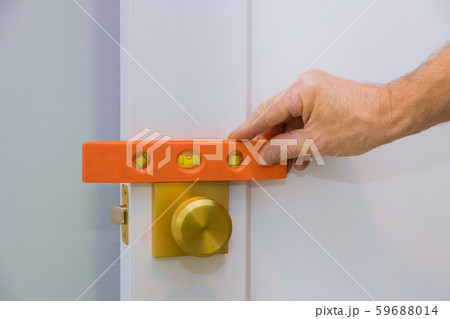 Male carpenter fixing lock in door with home 59688014