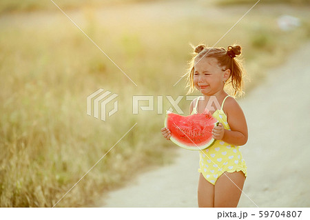 Beautiful little girl eating watermelon outdoors closeup photo Beautiful little girl eating watermelon outdoors closeup photo 59704807