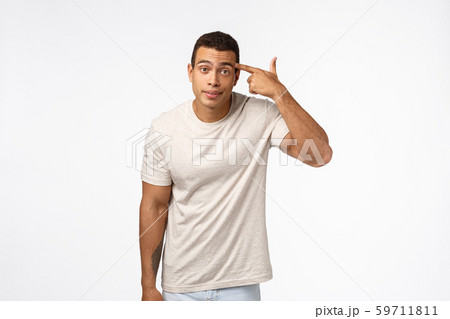 Annoyed arrogant and aggressive handsome brazilian guy rolling finger over temple and stare camera Annoyed arrogant and aggressive handsome brazilian guy rolling finger over temple and stare camera 59711811