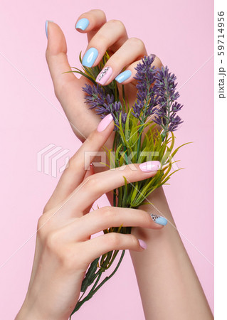 Beautiful pink and blue manicure with crystals on female hand with flowers. Close-up. Beautiful pink and blue manicure with crystals on female hand with flowers. Close-up. 59714956