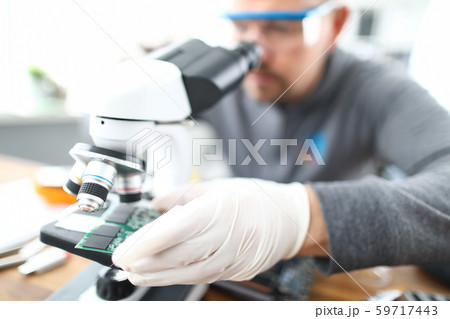 Man soldering using microscope Man soldering using microscope 59717443