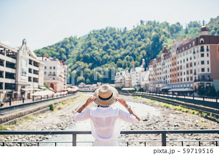 Happy girl at hat on the embankment of a mountain river in a European city. Happy girl at hat on the embankment of a mountain river in a European city. 59719516