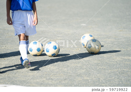 土のグラウンドにサッカー少年とサッカーボールの写真素材