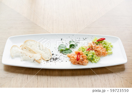 Salmon tartare with cucumber and sesame seeds. Tasting dish on a wooden table. 59723550