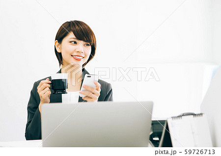 仕事の休憩中にスマホを見ながらコーヒーを飲む女性 仕事の休憩中にスマホを見ながらコーヒーを飲む女性 59726713