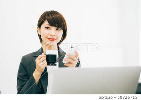仕事の休憩中にスマホを見ながらコーヒーを飲む女性 59726715