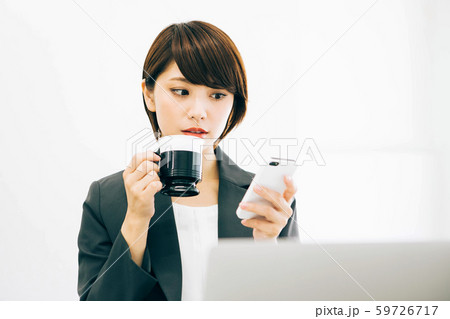 仕事の休憩中にスマホを見ながらコーヒーを飲む女性 仕事の休憩中にスマホを見ながらコーヒーを飲む女性 59726717
