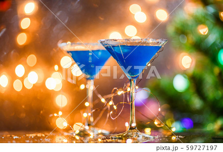 Christmas photo of two wine glasses with blue cocktail and garland 59727197