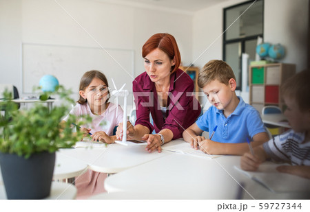 A group of small school kids with teacher sitting in circle in class, learning. A group of small school kids with teacher sitting in circle in class, learning. 59727344