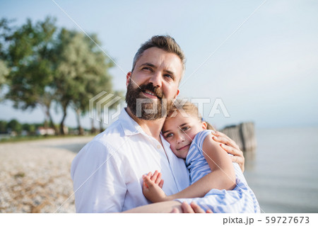 Side view of father and small daughter on a holiday sitting by the lake. Side view of father and small daughter on a holiday sitting by the lake. 59727673