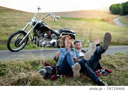 A cheerful senior couple travellers with motorbike in countryside. A cheerful senior couple travellers with motorbike in countryside. 59728466