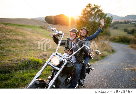 A cheerful senior couple travellers with motorbike in countryside. 59728467