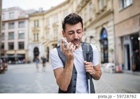 Young blind man with smartphone on street in city, making phone call. 59728762