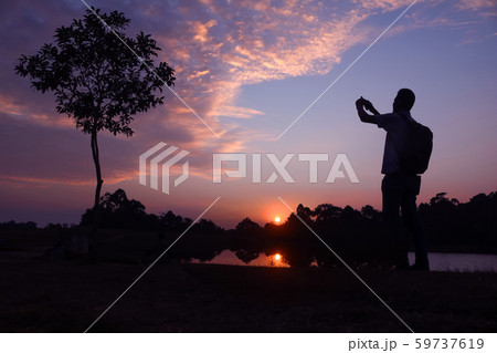 Photographer taking picture with camera at sunset Photographer taking picture with camera at sunset 59737619