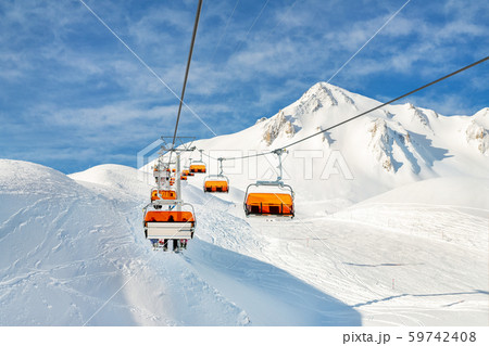 Ski lift ropeway on hilghland alpine mountain winter resort on bright sunny day. Ski chairlift cable Ski lift ropeway on hilghland alpine mountain winter resort on bright sunny day. Ski chairlift cable 59742408