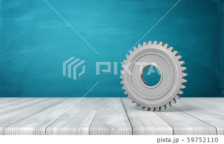 3d rendering of light-grey metal gearwheel standing on wooden floor near blue wall with some copy 59752110