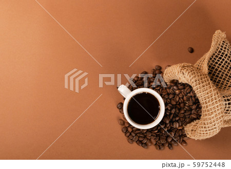 Hot coffee cup and coffee beans on brown Hot coffee cup and coffee beans on brown 59752448