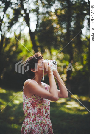 Active girl taking photo on instant camera in sunny forest 59752449