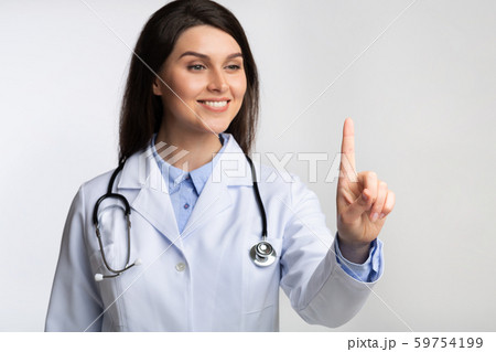 Smiling Doctor Touching Invisible Touchscreen Standing In Studio, Shallow Depth 59754199