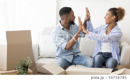Happy Afro Spouses Giving High-Five Sitting Among Moving Boxes Indoor 59756785