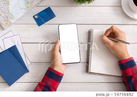 Man holding smartphone with blank screen and taking notes 59756892
