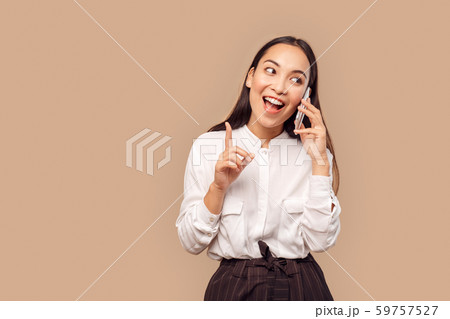 Freestyle. Young woman in shirt standing isolated on bage talking on smartphone pointing up creative Freestyle. Young woman in shirt standing isolated on bage talking on smartphone pointing up creative 59757527