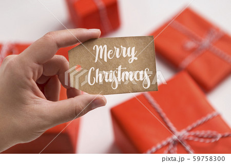 Woman hanging label with text on New Year gift boxes 59758300