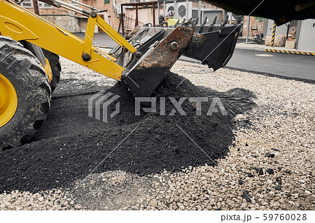 A tractor unloads the asphalt. Large heavy machinery is carrying out road repair work. Laying new 59760028