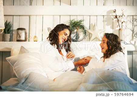 young mother with daughter in bed huggings, lifestyle people at home concept young mother with daughter in bed huggings, lifestyle people at home concept 59764694