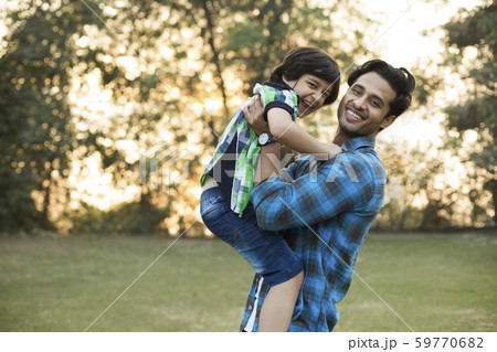 Smiling man playing with his happy son by lifting him in the park. 59770682
