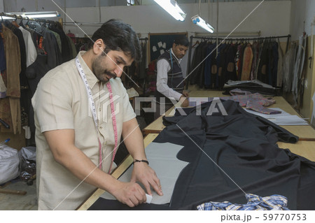 Tailor making markings on cloth in his workshop. Tailor making markings on cloth in his workshop. 59770753