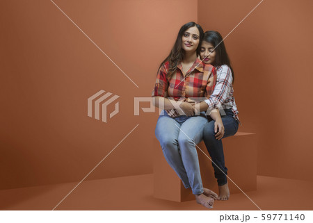 Studio shot of two young teenager girls holding each other Studio shot of two young teenager girls holding each other 59771140