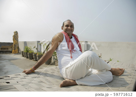 Indian man is sitting on a camp bed 59771612