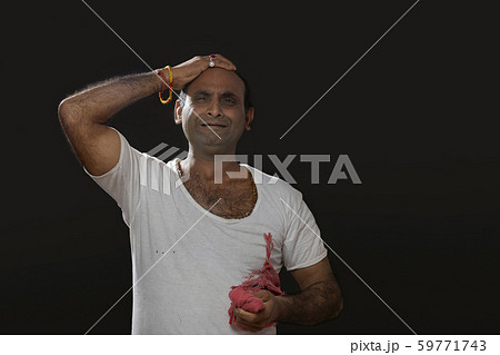 Depressed Indian farmer standing and holding his head in disbelief 59771743
