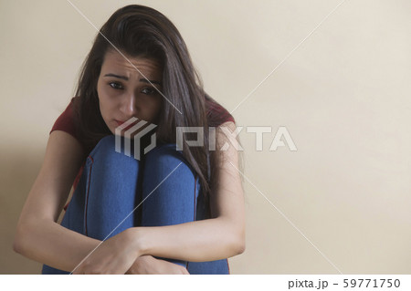 Young girl sitting alone in distress 59771750