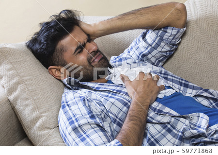 Man in pain on the sofa with tissues 59771868