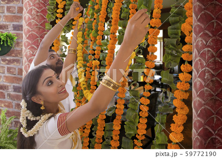 south indian couple decorating their home on onam 59772190