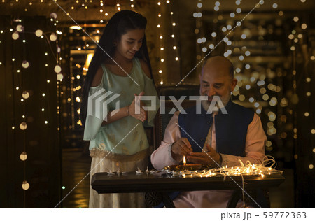 grand father and grand daughter preparing diyas together 59772363