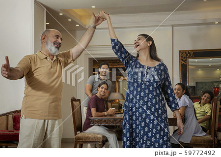 Grandparents dance in the living room while the family watches. Grandparents dance in the living room while the family watches. 59772492