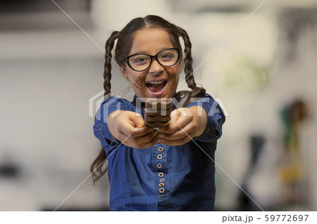 Happy girl in eyeglasses offering a chocolate bar holding it with both hands 59772697