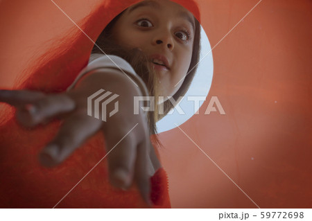 Close up of a girl extending her hand to pick something from an orange container Close up of a girl extending her hand to pick something from an orange container 59772698