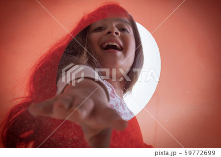 Close up of hand of a smiling girl picking something from an orange container 59772699