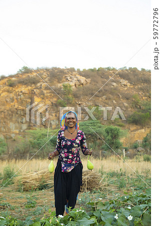 woman holding bottle gourd and smiling, in the field woman holding bottle gourd and smiling, in the field 59772796