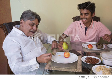 Grandson serving his grandfather on the dining table at home. 59772862